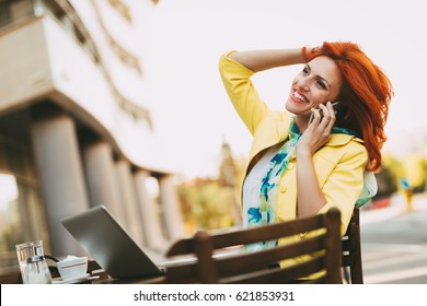 Successful businesswoman using phone on a coffee break in a street cafe.
