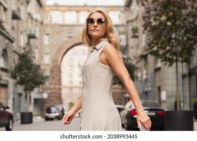 Successful caucasian businesswoman lady walking on city street. Mature middle-aged caucasian woman wearing sunglasses eyewear outdoors.