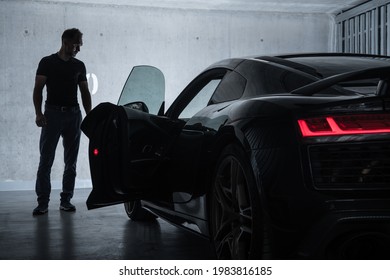 Successful Caucasian Men in His 40s Looking at His Luxury Exotic Car Inside Underground Garage. Car Enthusiast Collection.