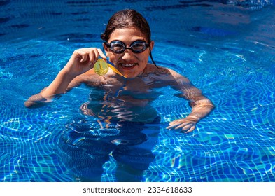 Successful caucasian young swimmer with award in outdoor pool. Golden trophy in swimming, teen boy showing off medal. Healthy lifestyle concept, sport activities - Powered by Shutterstock