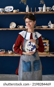 Successful Ceramics Studio Owner Posing With Handmade Plate At Workplace. Confident Entrepreneur Crafts Woman In Pottery Studio With Creating Handicraft Potter Dish In Workshop