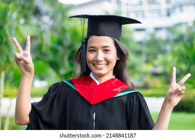 Successful college student in commencement day showing v for victory, education success