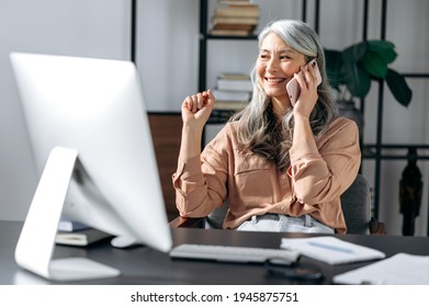 Successful Confident Beautiful Senior Gray-haired Asian Woman, Business Leader, Manager, Working At The Office, Talking On The Phone With Friends Or Colleagues, Looking Away, Smiling