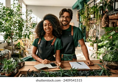 Successful, confident business man and business woman, florists and gardeners sell plants, decor and flower pots in their greenhouse.Our family business.Creative green space, gardening center. - Powered by Shutterstock