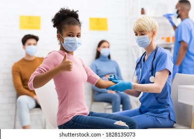 Successful Coronavirus Vaccination. Happy Vaccinated Black Teen Girl Gesturing Thumbs Up After Covid-19 Vaccine Injection In Hospital. Corona Virus Protection And Immunization. Selective Focus