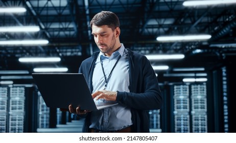Successful Data Center IT Specialist Using Laptop Computer. Server Farm Cloud Computing Facility with System Administrator Working. Data Protection Engineering Network for Cyber Security.