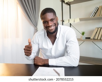 Successful deal. Corporate agreement. Cooperation offer acceptance. Satisfied smiling business man approving contract with thumb up like gesture at office workplace interior.