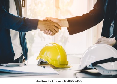 Successful deal, male architect shaking hands with client in construction site after confirm blueprint for renovate building.