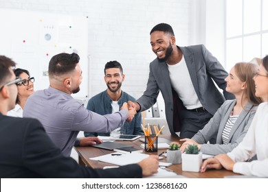Successful deal. Two businessmen shaking hands, sitting at desk in office