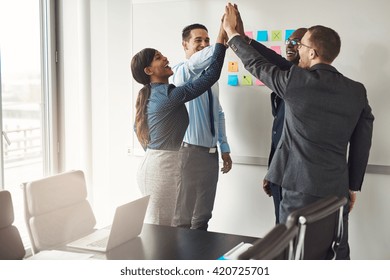 Successful Diverse Multiracial Business Team Giving A High Fives Gesture As They Celebrate In A Conference Room In An Office