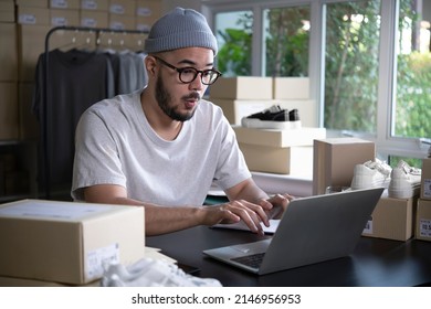 Successful E-commerce Asian Business Man. Happy Young Male Online Seller Taking Note Of Orders From Customers. Drop Shipping Business Owner Working In His Store Warehouse.