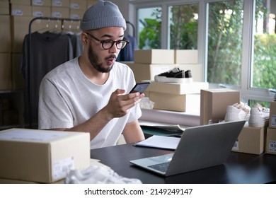 Successful E-commerce Asian Business Man. Happy Young Male Online Seller Taking Note Of Orders From Customers. Drop Shipping Business Owner Working In His Store Warehouse.