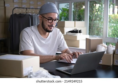 Successful E-commerce Asian Business Man. Happy Young Male Online Seller Taking Note Of Orders From Customers. Drop Shipping Business Owner Working In His Store Warehouse.