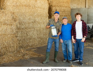 Successful Elderly Dairy Farm Owner With Adult Son And Teen Grandson Standing Together Near Straw Stack In Hayloft After Work