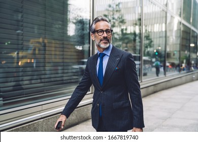 Successful elegant middle aged male executive in expensive suit walking purposefully on New York City street and turning head to side - Shutterstock ID 1667819740