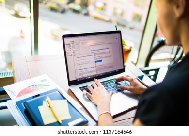 Successful entrepreneur checking e-mail on laptop computer, sitting in coffee shop during business trip. Woman commercial real estate analyst keyboarding on notebook. Female advertiser typing text 