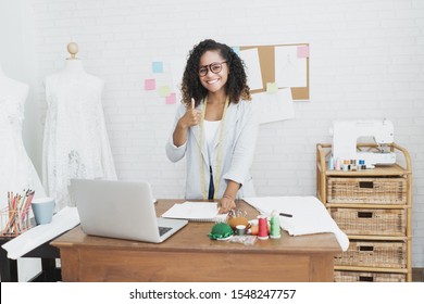 Successful entrepreneur Fashion Designer. Cheerful young African American Fashion Designer Stylish thumbs up posing and smiling at looking camera in her studio. SME and Small Business Concept.