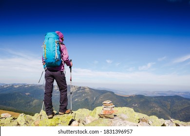 Successful Female Hiker With Backpack Observing On Mountain Peak