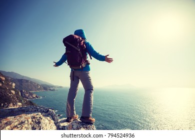 successful female hiker stand on sunrise seaside mountain cliff edge - Powered by Shutterstock