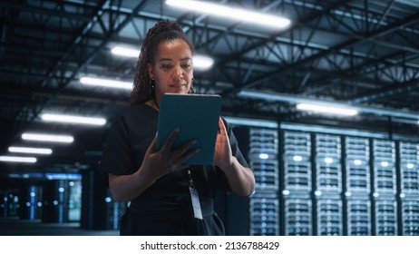 Successful Female IT Specialist Using Laptop Computer, while Standing at Big Warehouse Data Center. System Administrator working with Computing SAAS, Cloud Services. E-Business Digital Entrepreneur