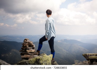 Successful Fitness Woman Climbing Through The Rocks To The Top Of The Mountain