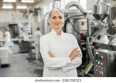 A successful food plant supervisor smiling at the camera with arms crossed. - Powered by Shutterstock