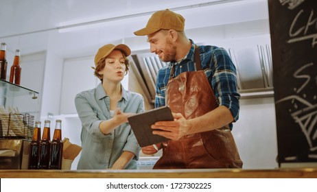 Successful Food Truck Man and Woman Employees in Brown Caps are Using a Tablet Computer. They Discuss Their Profits and Future Business Plans. Commercial Truck or Kiosk Selling Street Food and Drinks. - Powered by Shutterstock