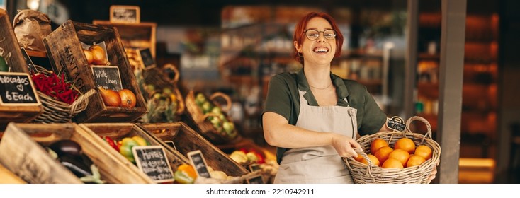 Successful grocery store owner smiling at the camera while holding a basket of fresh organic grapefruits. Happy female entrepreneur running a small business in the food industry. - Powered by Shutterstock