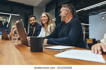 Successful group of businesspeople having a briefing in a boardroom. Happy businesspeople smiling while working together in a modern workplace. Diverse business colleagues collaborating on a project.