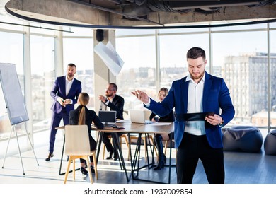 Successful Handsome Male Mentor, Director, Businessman In A Suit At The Office. Working Day Concept. Team Meeting With The Boss In The Foreground