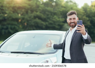 Successful and happy man brags about buying a new car, having fun talking to friends uses a video call in the phone app - Shutterstock ID 2109306578