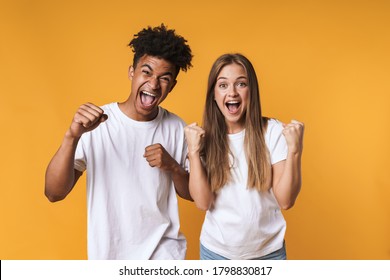 Successful happy multiethnic couple celebrating success isolated over yellow - Shutterstock ID 1798830817