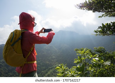 Erfolgreicher Wanderer mit Smartphone auf der Bergspitze  