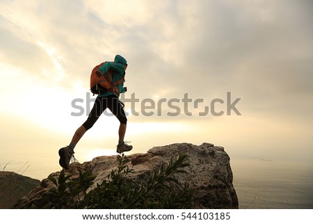 successful hiker walking on seaside mountain top cliff edge