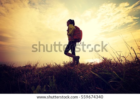 successful hiker walking on seaside mountain peak  