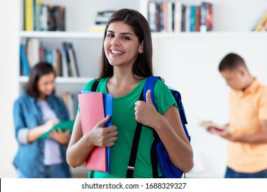 Successful Hispanic Female Student With Group Of Young Adults At Classroom Of University