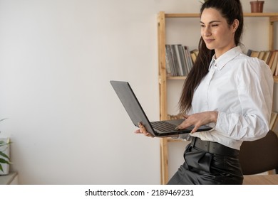 Successful Hispanic Millennial Woman Using And Typing On Laptop In Modern Office Looking At Camera. Female In Business Concept.