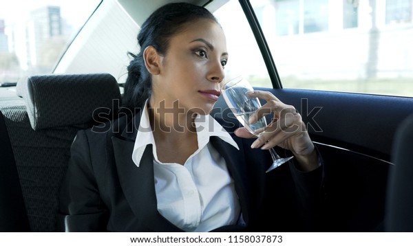 Successful lady drinking champagne in car,\
celebrating business success,\
career