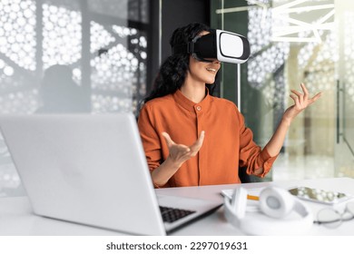 Successful latin american woman in office using vr glasses for video call and chatting online in virtual reality simulator, online conference with colleagues remote in metaverse. - Powered by Shutterstock