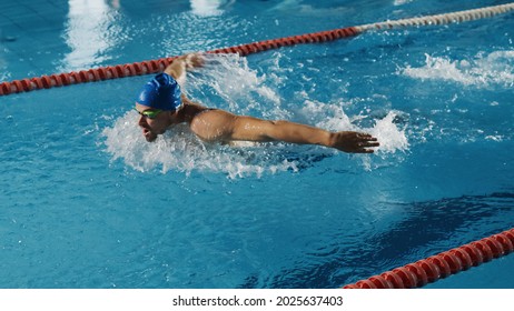 Successful Male Swimmer Racing, Swimming In A Swimming Pool. Professional Athlete Determined To Win Championship Using Butterfly Style. Colorful Cinematic Shot.