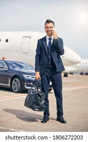 Successful man looking business-like holding a duffel bag standing in front of an airplane