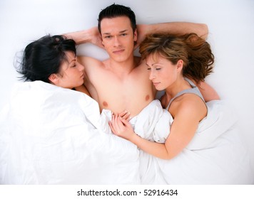 Successful man lying with two girls in bed