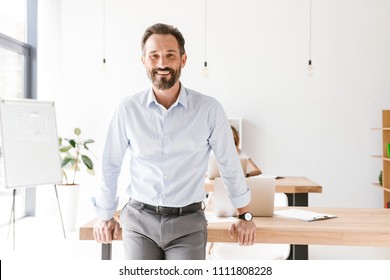 Successful Man Manager Leaning On A Desk While Standing At The Office With Woman Co Worker On A Background