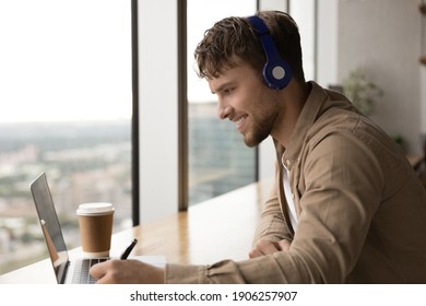 Successful Man Student Sit By Laptop Take Part In Virtual Training Glad Of Making Progress In Distant Learning. Skilled Young Male Translator In Headphones Engaged In Work By Video Remote Interpreting