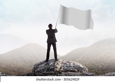 Successful Man Waving Blank Flag On The Mountain. You Can Put Your Design On The Flag