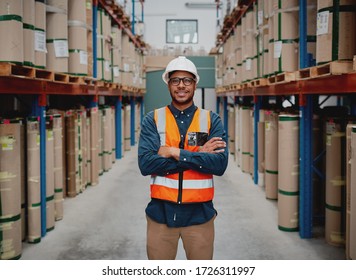 Successful Manufacturing Unit Worker Standing In Warehouse Distribution Centre With Folded Hands With Helmet And Uniform Smiling