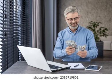 Successful mature banker financier investor at workplace counting money dollars cash, senior businessman boss inside office happy with achievement results. - Powered by Shutterstock