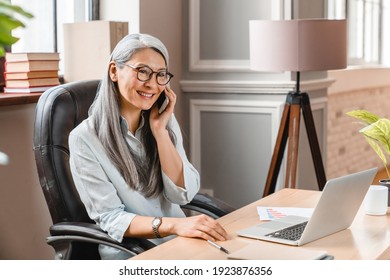 Successful mature business woman talking on phone at working place in office - Powered by Shutterstock