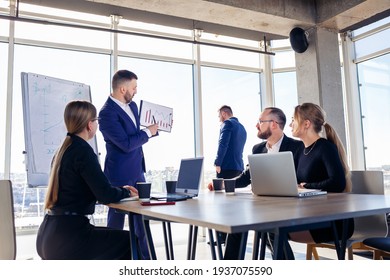 Successful meeting of business people, discussing new business ideas, using diagrams, sitting together. Modern office background. Meeting of business partners at the conference on business development