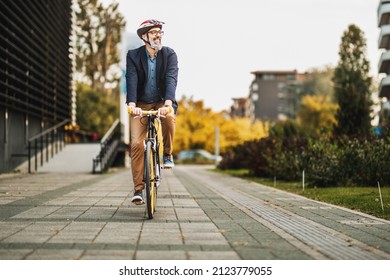 Successful middle-aged businessman riding bicycle on his way to work through the city. - Powered by Shutterstock